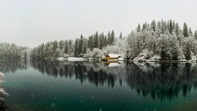 Serene Yellow Cabin by a Snowy Alpine Lake Winter Desktop Wallpaper