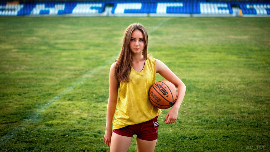 Beautiful Sporty Girl Holding a Basketball on a Stadium Field Desktop Wallpaper