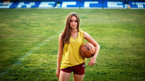 Beautiful Sporty Girl Holding a Basketball on a Stadium Field Desktop Wallpaper